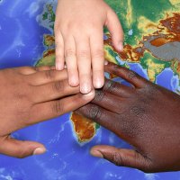Drei Kinderhände liegen übereinander auf einem Globus Drei Kinderhände liegen übereinander auf einem Globus
