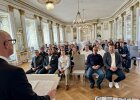 Blick von hinten über das Rednerpult von Regierungspräsident Walter Jonas auf die Geehrten, die im Großen Sitzungssaal der Regierung der Oberpfalz sitzen.