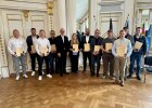 Gruppenfoto mit Regierungspräsident Walter Jonas und den elf Geehrten der Lebensretter-Ehrung in der Regierung der Oberpfalz, alle halten ihre Urkunden in den Händen.
